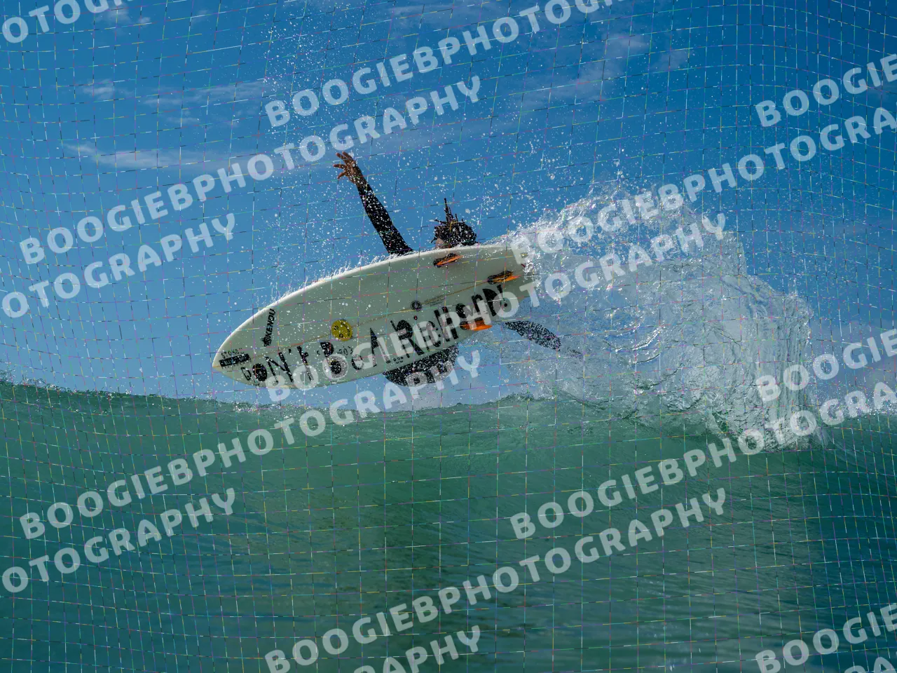 Surfer launching off the lip with one arm raised, the board turned to show a hand-lettered deck reading "DON'T BE A RICHARD!" against blue sky.