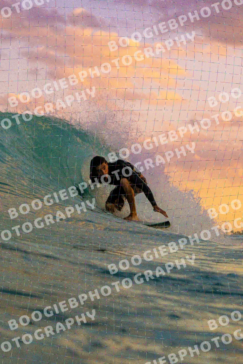 Surfer tucked into a barrel under a purple and orange sunset sky.